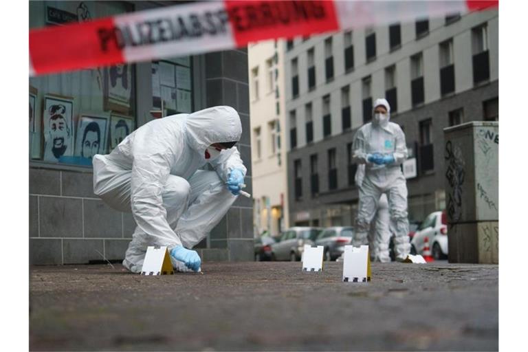 Beamte der Spurensicherung sichern Blutspuren auf dem Gehweg in der Frankfurter Niddastraße. Foto: Frank Rumpenhorst/dpa