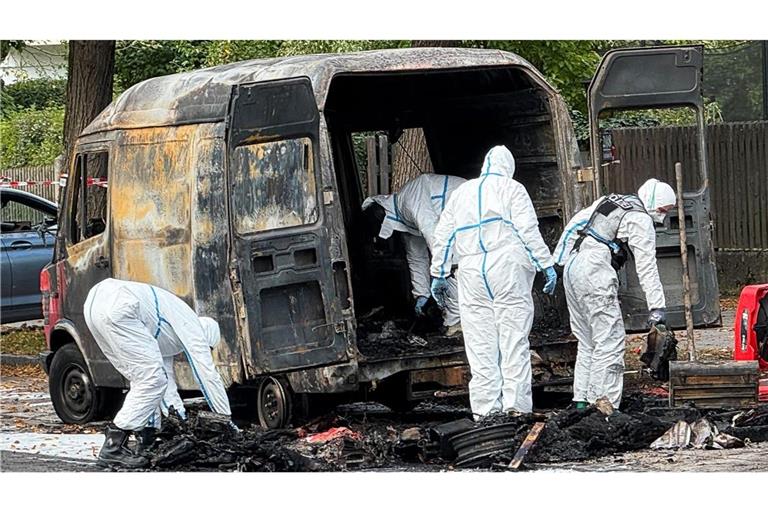 Beamte der Spurensicherung untersuchen einen ausgebrannten Transporter nach einem Brand in einem Einfamilienhaus im Münchner Stadtteil Lerchenau.