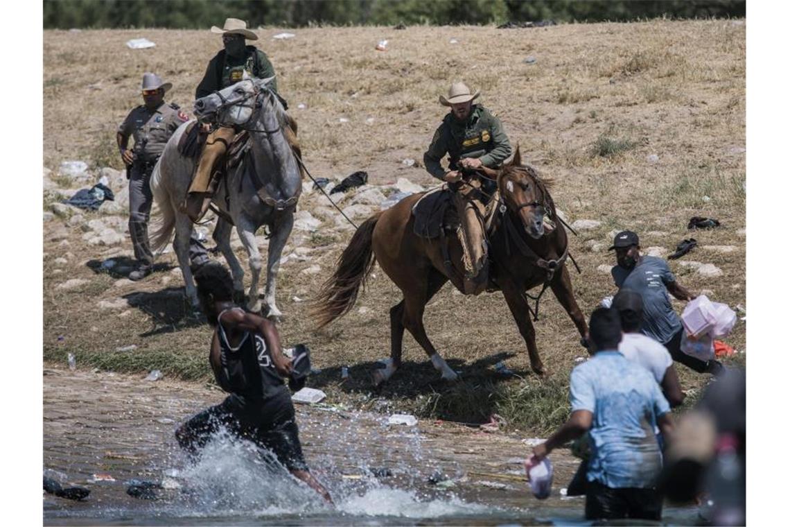 Einsatz gegen Migranten - Kritik an US-Beamten auf Pferden Beamte der US-Zoll- und Grenzschutzbehörde versuchen auf Pferden, Migranten an der Überquerung des Grenzflusses Rio Grande zu hindern. Foto: Felix Marquez/AP/dpa