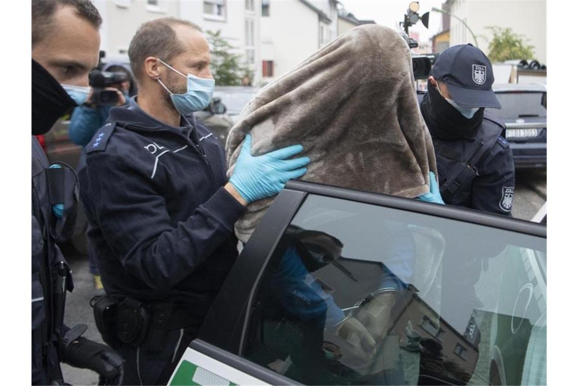 Beamte des Zoll führen den in Frankfurt festgenommenen Hauptbeschuldigten mit einer Decke über dem Kopf ab. Bei dem in Frankfurt festgenommenen Mann handelt es sich um einen Mann aus dem Umfeld der Hells-Angels. Foto: Boris Roessler/dpa