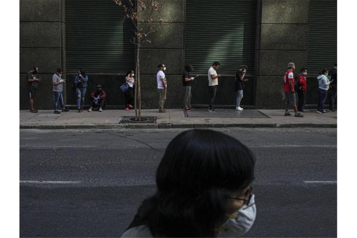 Droht schlimmste Entwicklung seit der Weltwirtschaftskrise? Bedürftige stehen in Santiago de Chile in einer Schlange an, um Arbeitslosengeld zu bekommen. Foto: Esteban Felix/AP/dpa