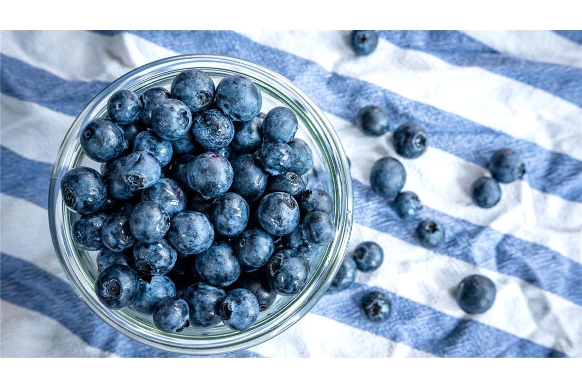 Die Heidelbeere, die Kim Kardashian des Obstkorbs Beeren statt Chips oder Nüsschen: Heidelbeeren, auch Blaubeeren genannt, liegen auf einem Esstisch und werden gern gesnackt.