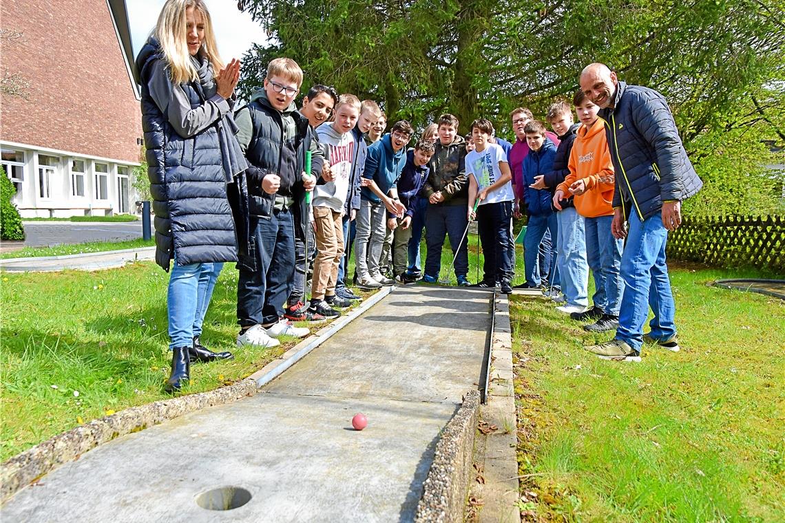 Backnangs einzige Minigolfanlage wieder eröffnet Bei der Einweihung freuen sich Konrektorin Ines Fabisch (links), Pfarrer Tobias Weimer (Mitte, lila Pullover) und Techniklehrer Peter Noki (rechts) mit den Schülern. Foto: Tobias Sellmaier