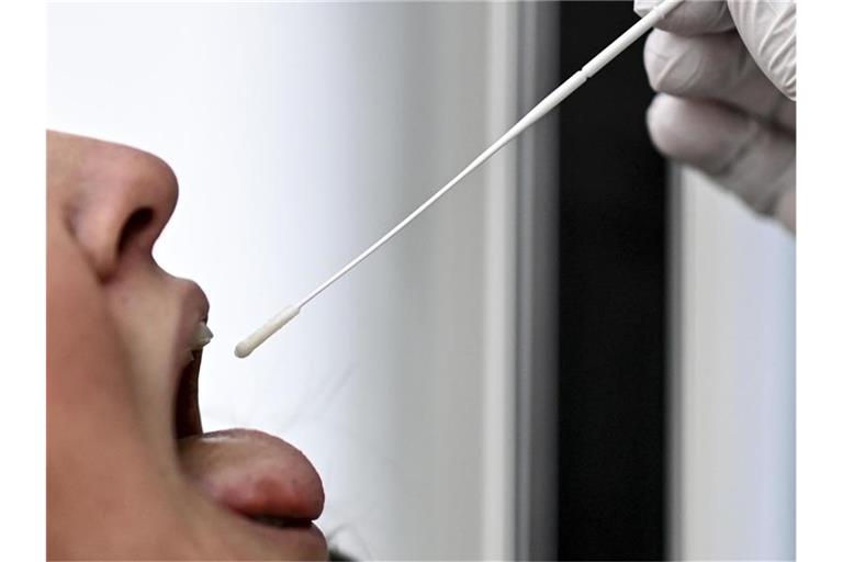 Bei einer jungen Frau wird ein Rachenabstrich für einen SARS-CoV-2-Antigentest durchgeführt. Foto: Britta Pedersen/dpa-Zentralbild/dpa