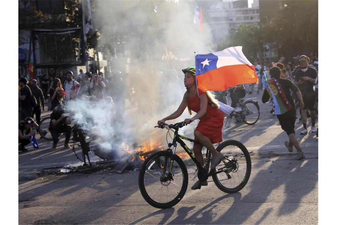 Bei einer Protestaktion gegen die Regierung hat eine junge Frau in Santiago ihr Fahrrad mit der chilenischen Flagge ausgestattet. Foto: Rodrigo Abd/AP/dpa