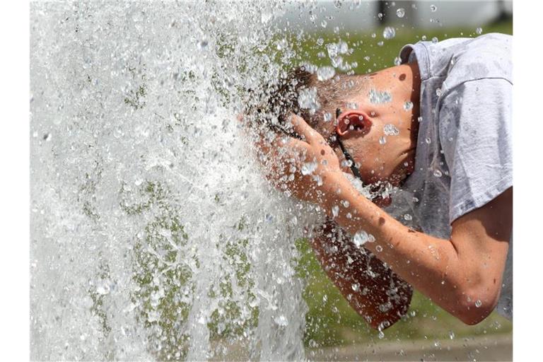 Bei noch sehr erträglichen Temperaturen um 29 Grad erfrischt sich ein junger Mann im Berliner Lustgarten an einem Brunnen. In den kommenden Tagen sollen die Temperaturen weiter steigen. Foto: Wolfgang Kumm