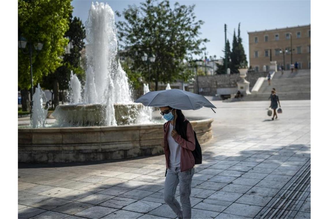 Südeuropa leidet unter Waldbränden und Gluthitze Bei Temperaturen über 40 Grad schützt sich eine Frau auf dem Syntagma-Platz in Athen mit einem Schirm gegen die Sonne. Foto: Angelos Tzortzinis/dpa