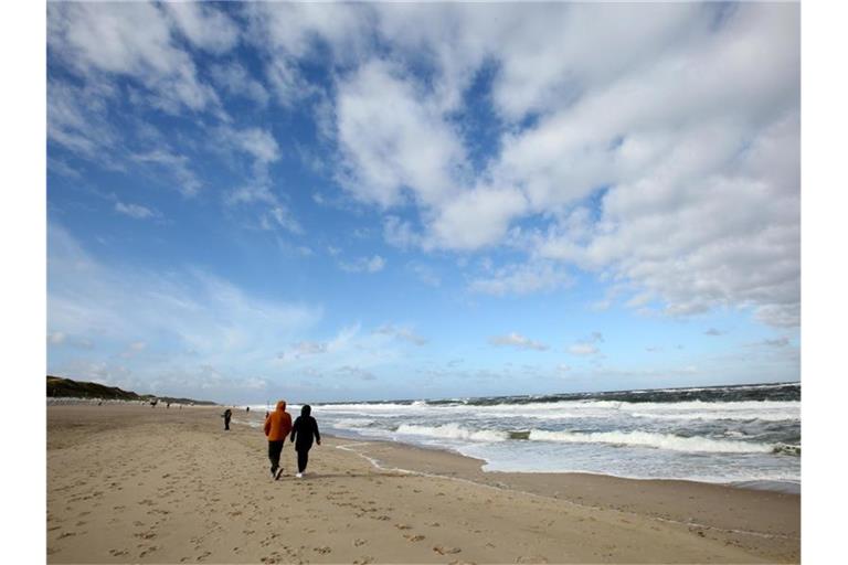 Bei windigem Wetter sind Spaziergänger am Strand von Westerland auf Sylt unterwegs. Foto: Bodo Marks/dpa