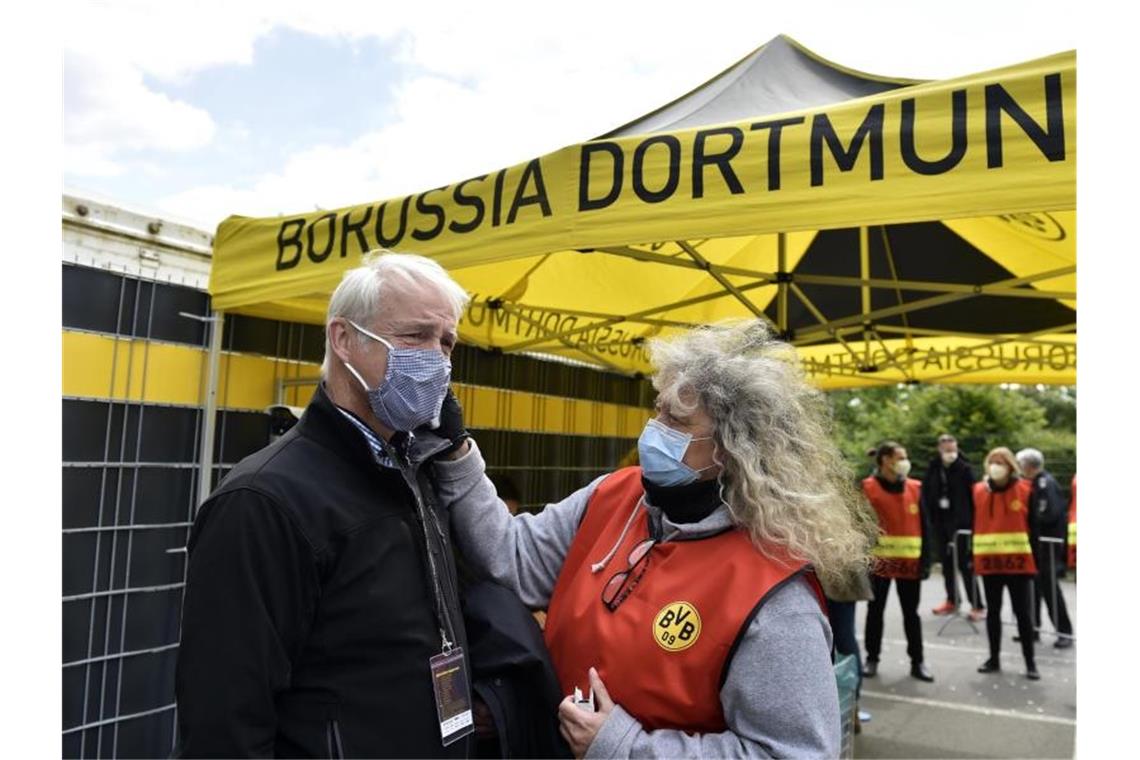 Beim Mitglied einer TV-Crew wird vor dem Einlass ins Stadion die Temperatur gemessen. Foto: Martin Meissner/AP-Pool/dpa