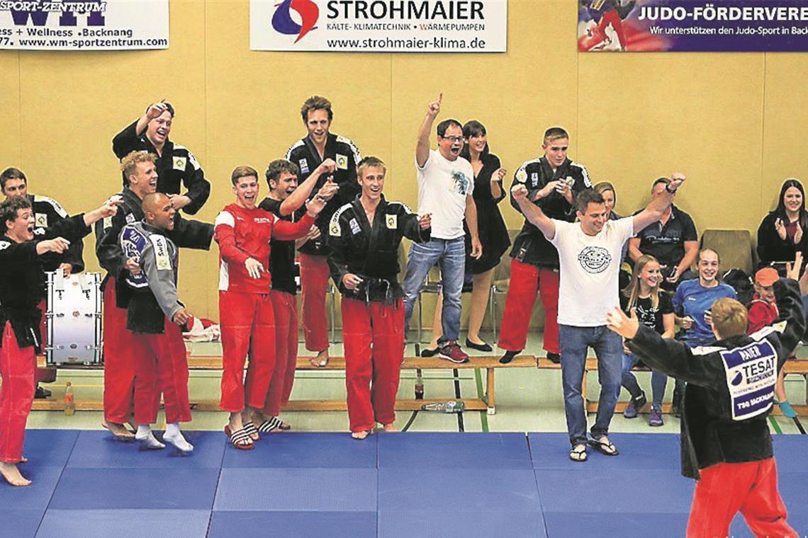 Bejubelten ihr Meisterstück und den wahrscheinlichen Aufstieg in die erste Liga: Backnangs Judokas um Trainer Jens Holderle (stehend Zweiter von rechts). Mit Leon Maier (rechts) war es ein Eigengewächs, das den achten Punkt beisteuerte. Foto: A. Becher