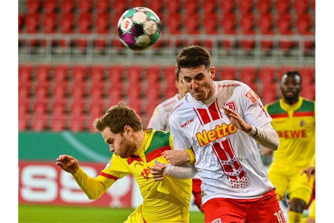 DFB-Pokal: Köln-Aus, Jahn-Jubel, Schalke-Pech Benno Schmitz vom 1. FC Köln (l) und Kaan Caliskaner von Jahn Regensburg beim Kopfballduell. Foto: Armin Weigel/dpa