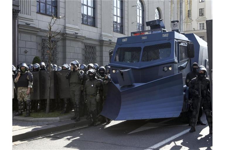 Bereitschaftspolizisten blockieren eine Straße mit einem Militärfahrzeug in Minsk. Foto: ---/AP/dpa