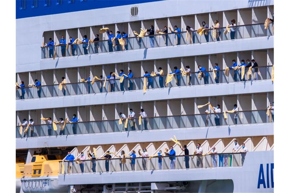 Aida will Mittelmeer-Kreuzfahrten wieder aufnehmen Besatzungsmitglieder winken mit Handtüchern von den Balkons eines Aida-Kreuzfahrtschiffs, das in den Hafen von Rostock einläuft. Foto: Jens Büttner/dpa-Zentralbild/dpa