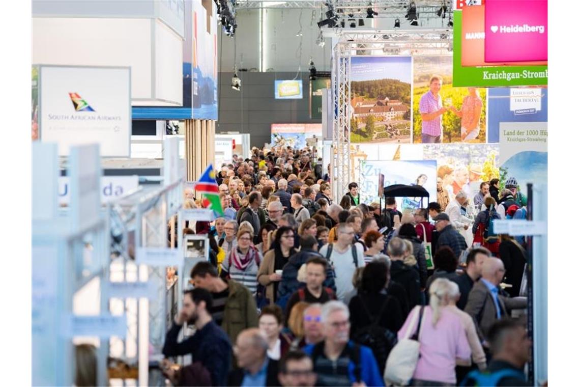 Besucher gehen bei der Reisemesse CMT durch eine Halle der Messe Stuttgart. Foto: Tom Weller/dpa