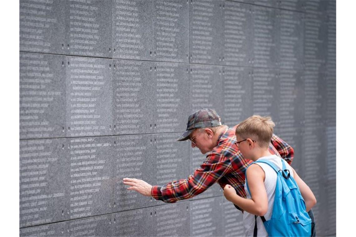 Besucher lesen auf einer Gedenkmauer Namen von Opfern des Warschauer Aufstands. Foto: Kay Nietfeld