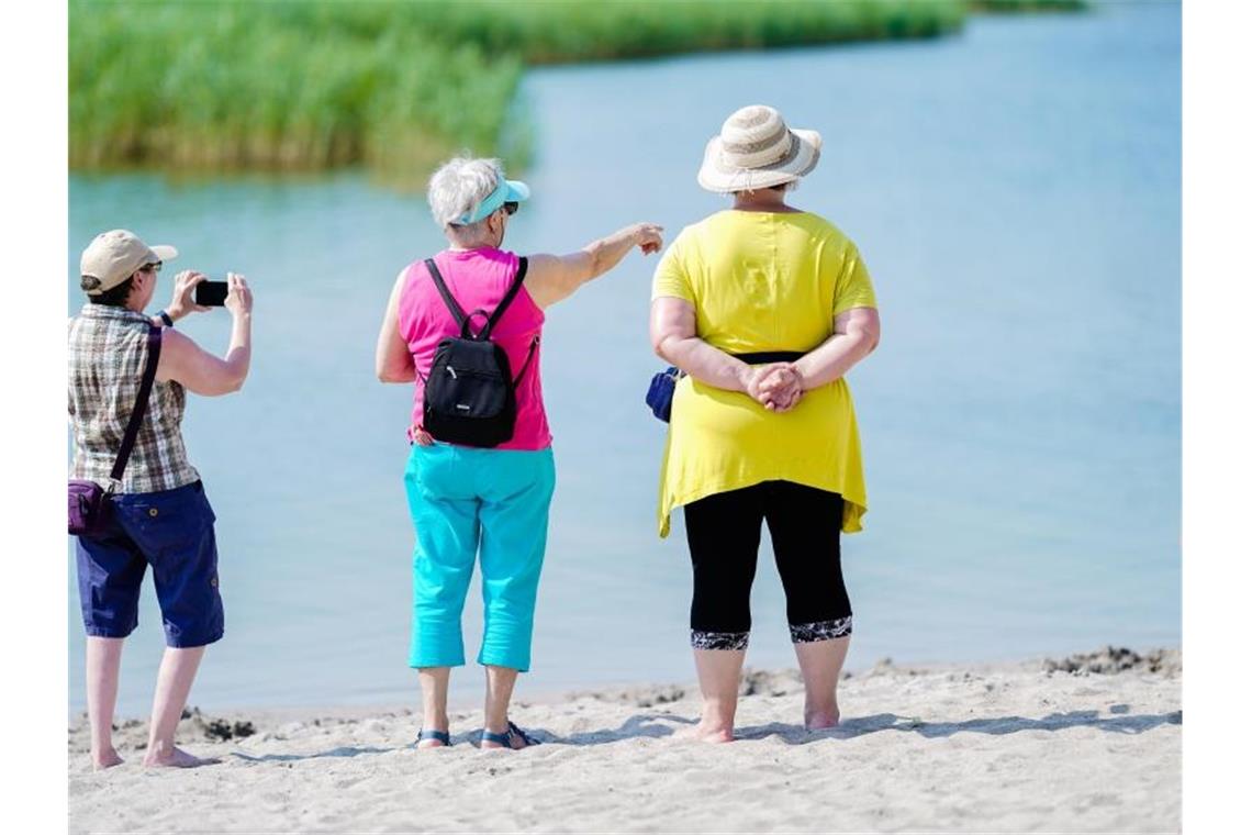 Besucher stehen auf dem Gelände der Bundesgartenschau am Sandstrand vom Karlssee. Foto: Uwe Anspach/Archivbild