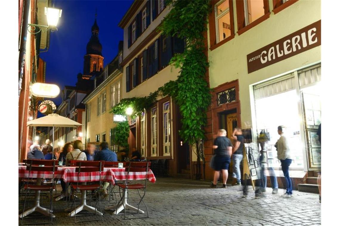 Besucher stehen in der Altstadt von Heidelberg. Foto: Uwe Anspach/dpa/Archivbild