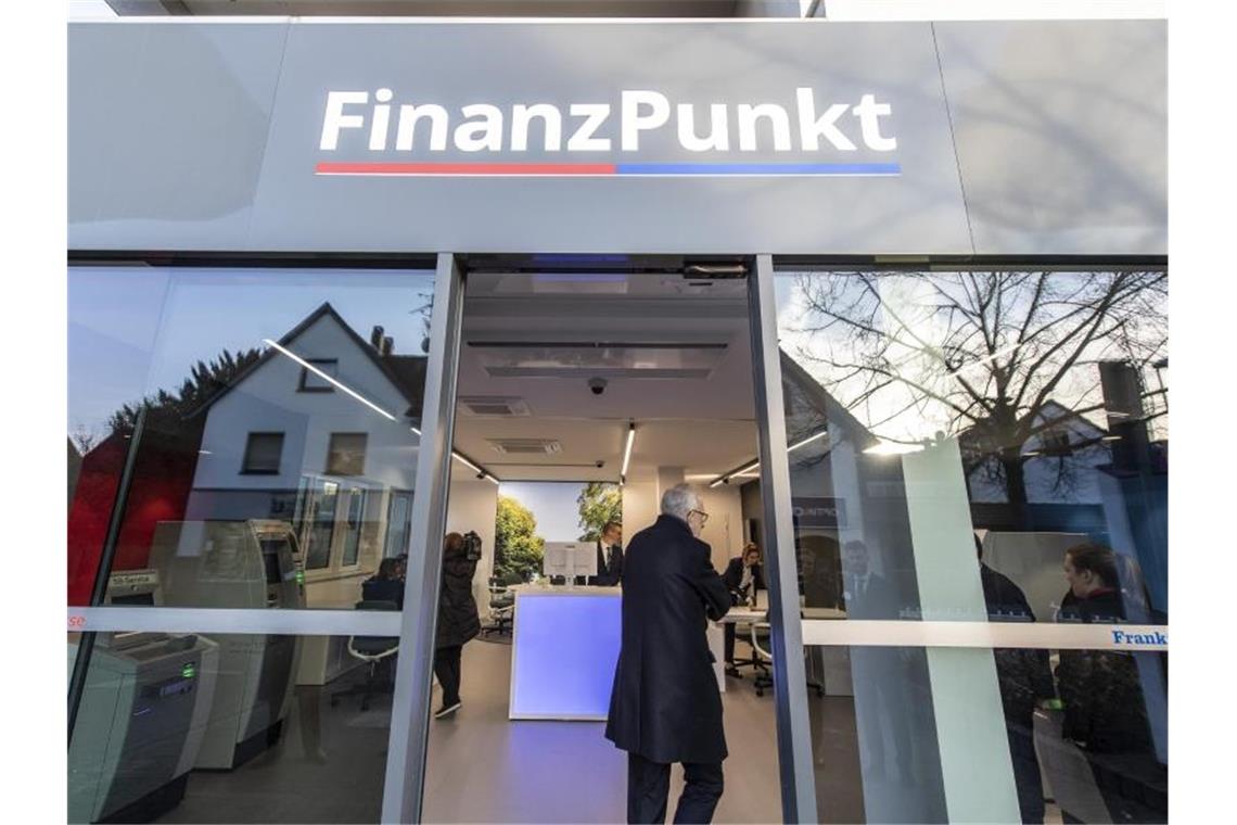 Besucher stehen zur Eröffnung vor dem „Finanzpunkt“. In der Bankfiliale kooperieren die Taunus Sparkasse und die Frankfurter Volksbank. Foto: Boris Roessler/dpa