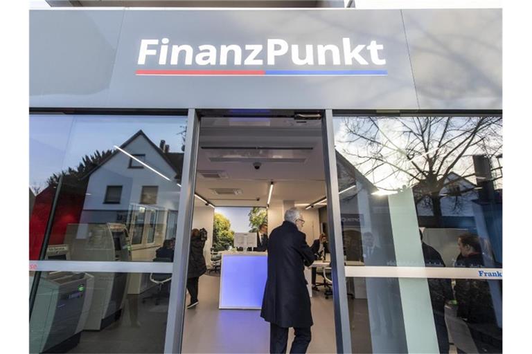 Besucher stehen zur Eröffnung vor dem „Finanzpunkt“. In der Bankfiliale kooperieren die Taunus Sparkasse und die Frankfurter Volksbank. Foto: Boris Roessler/dpa