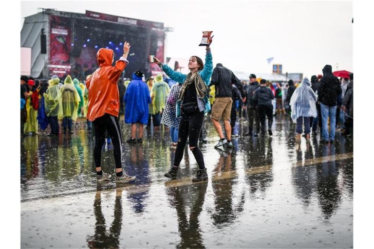 Besucherinnen tanzen am Samstag trotz anhaltenden Regens auf dem Southside Festival vor der Bühne. Foto: Christoph Schmidt