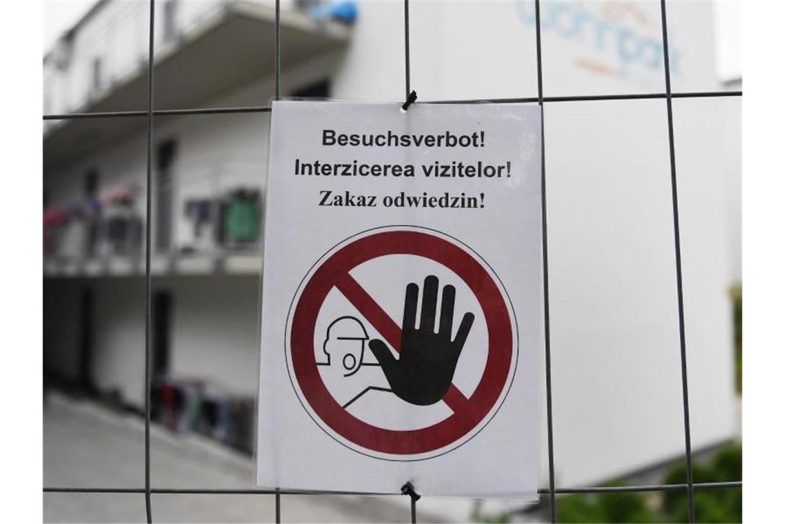 „Besuchsverbot!“ steht auf deutsch, rumänisch und polnisch auf einem Zettel an einem Bauzaun, der die Wohngebäude eines Betriebes umzäunt. Foto: Angelika Warmuth/dpa