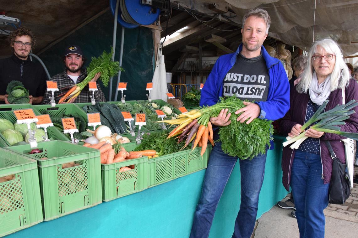 Spiegelberger Gärtnerei informiert über Solidarische Landwirtschaft Betriebsinhaber Florian Keimer und Amtsmitarbeiterin Christa Schumacher betonen vor dem Marktstand die Bedeutung des frischen Gemüses. Die Marktverkäufer der Gärtnerei „Johannes und Hannes“ im Hintergrund werben ebenfalls für hohe Qualität. Foto: Elisabeth Klaper