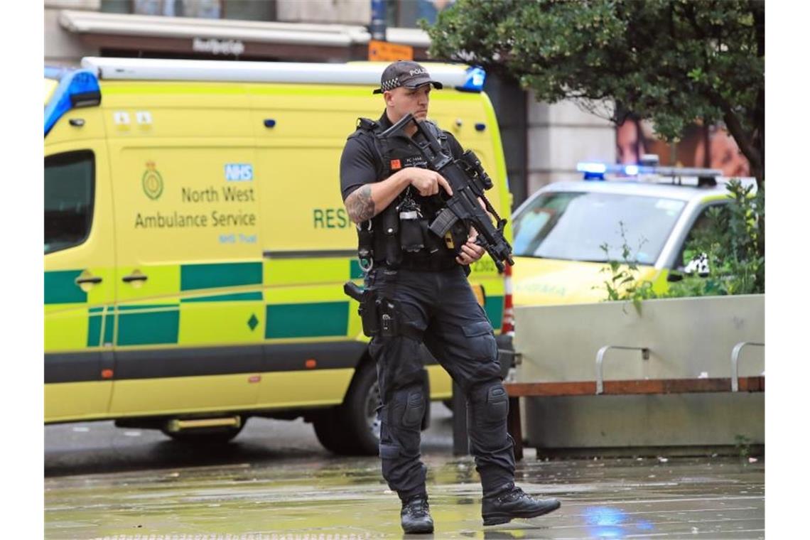 Bewaffnete Polizeibeamte stehen nahe dem Einkaufszentrum vor einem Krankenwagen. Foto: Peter Byrne/PA Wire/dpa