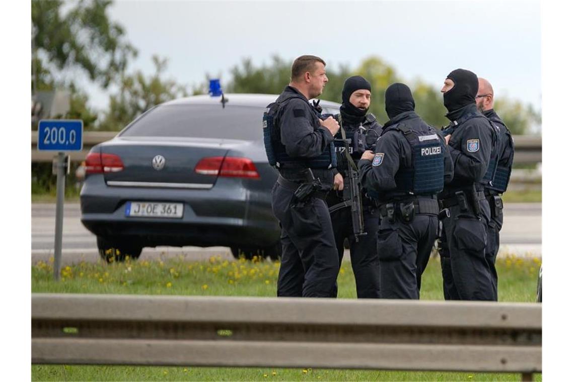 Bewaffnete Polizisten stehen mit zivilen Einsatzfahrzeugen an der Autobahnabfahrt Nohra. Foto: Johannes Krey/ZB/dpa