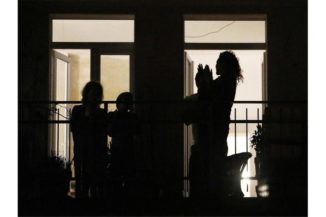 „Ode an die Freude“ vom Balkon aus: Musiker spielen mit Bewohner eines Hauses stehen auf ihrem Balkon und klatschen. Foto: Oliver Berg/dpa/Archivbild