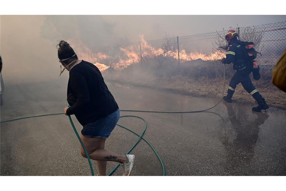 Kampf gegen Wind und Flammen in Griechenland Bewohner und Feuerwehrleute bekämpfen die Flammen.
