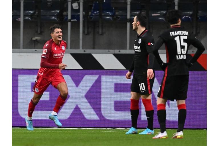 Bielefelds Alessandro Schöpf (l) feiert sein Tor zur 2:0-Führung neben den Frankfurtern Filip Kostic (M) und Daichi Kamada. Foto: Arne Dedert/dpa