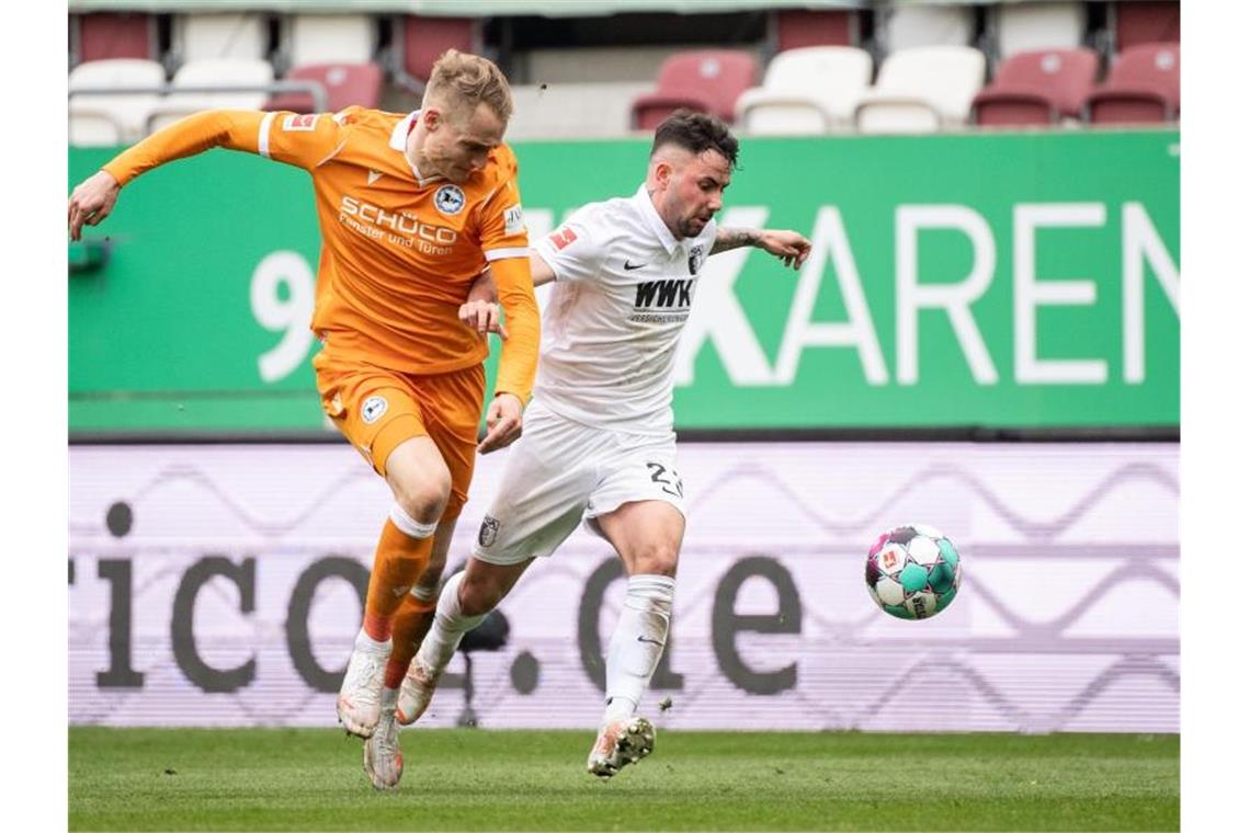 Bayern gewinnt in Wolfsburg - Flick kündigt Abschied an Bielefelds Amos Pieper (l) und Augsburgs Marco Richter im Zweikampf um den Ball. Foto: Matthias Balk/dpa