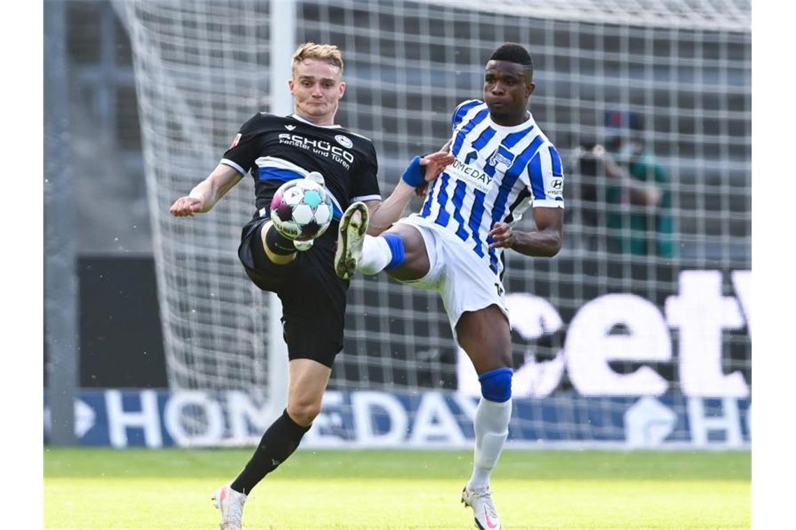 Bielefelds Amos Pieper und Herthas Jhon Cordoba (r) gehen mit gestreckten Beinen zum Ball. Foto: Soeren Stache/dpa-Pool/dpa