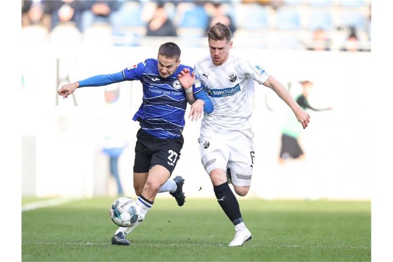 Bielefelds Cedric Brunner (l) im Kampf um den Ball mit Denis Linsmayer (r) aus Sandhausen. Foto: Friso Gentsch/dpa