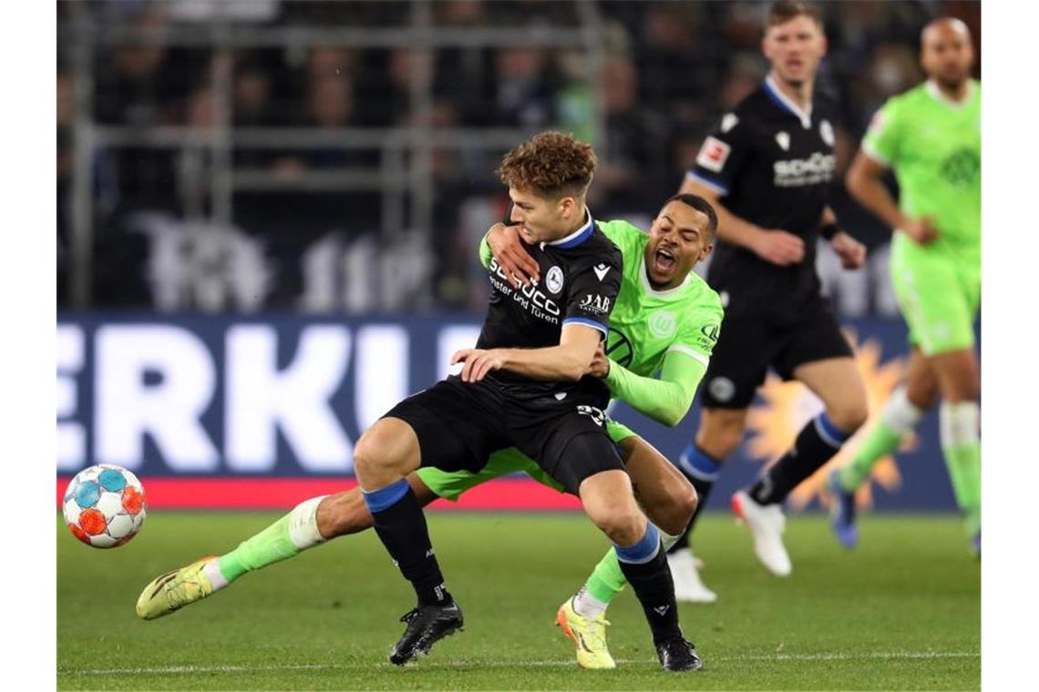 Bielefelds Cedric Brunner (l) und Wolfsburgs Lukas Nmecha kämpfen um den Ball. Foto: Friso Gentsch/dpa