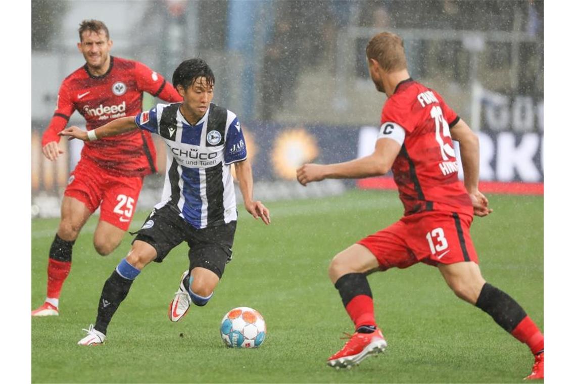 Bielefelds Masaya Okugawa (M) zieht im Dribbling gegen Frankfurts Martin Hinteregger (r) ins Eins gegen Eins. Foto: Friso Gentsch/dpa