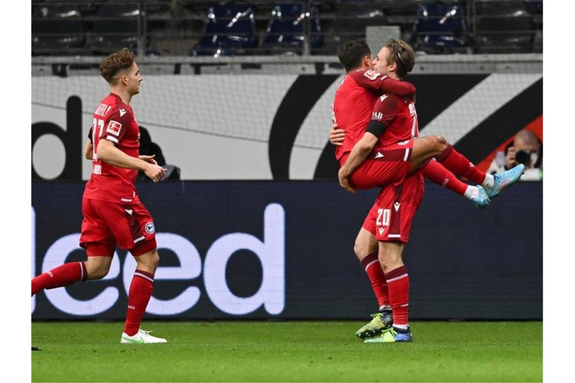 „Rabona“-Trick von Wimmer lässt auch Österreich jubeln Bielefelds Torschütze Alessandro Schöpf (M) springt Vorlagengeber Patrick Wimmer in die Arme. Foto: Arne Dedert/dpa