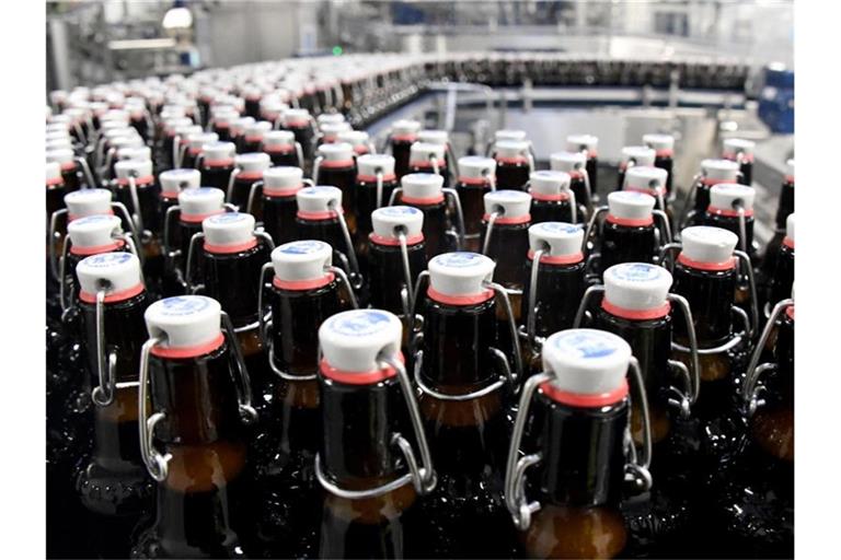 Bierflaschen laufen über ein Band in der Flensburger Brauerei. Foto: Carsten Rehder/dpa