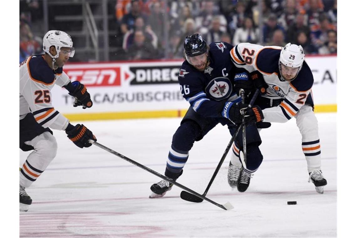 Blake Wheeler (M.) von den Winnipeg Jets im Zweikampf mit Leon Draisaitl (r). Foto: Fred Greenslade/The Canadian Press/AP/dpa