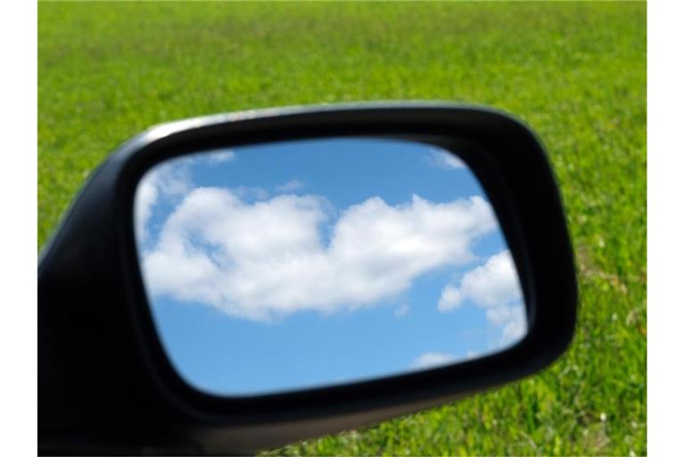 Blauer Himmel und Wolken im Außenspiegel eines Autos. Foto: Sebastian Willnow/dpa-Zentralbild/dpa