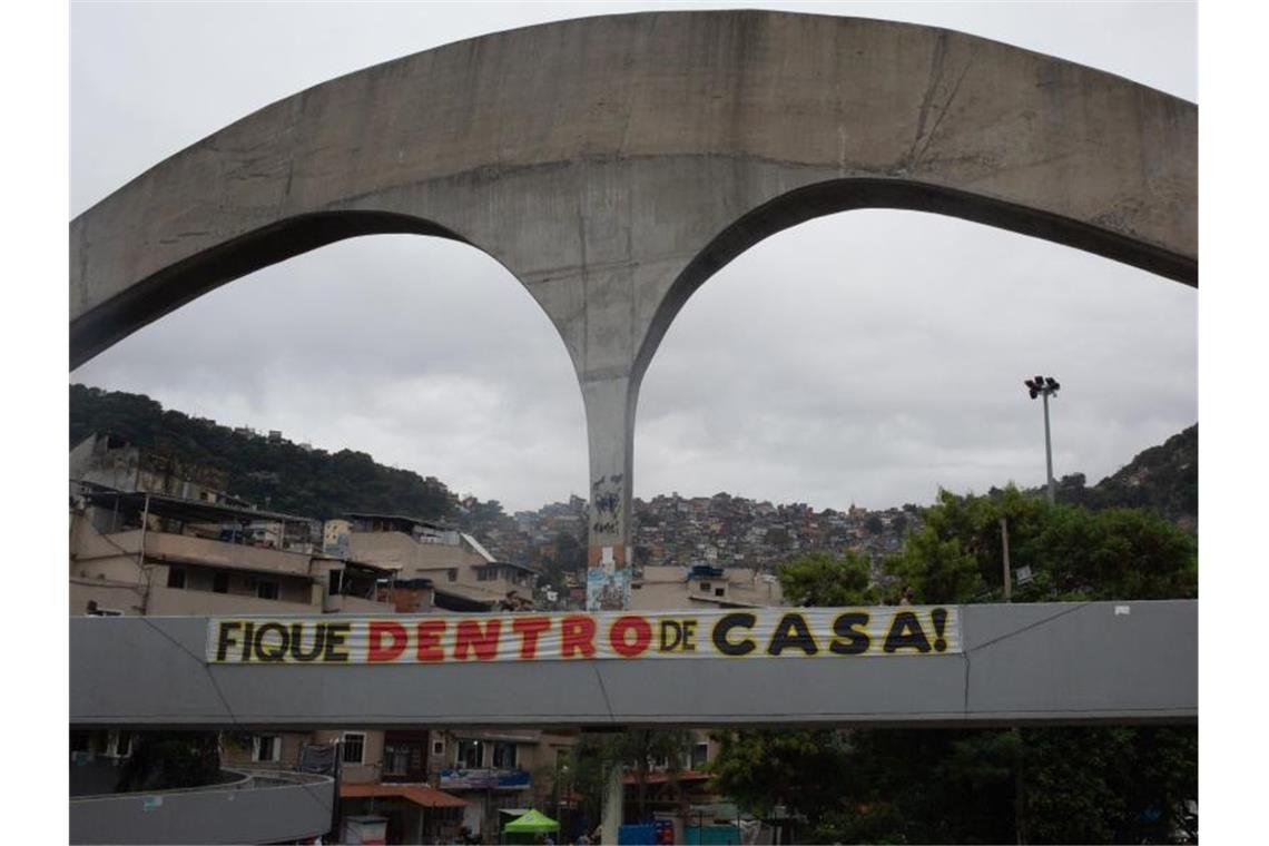 „Bleibt zu Hause!“, steht an einer Brücke am Eingang der Favela Rocinha. Foto: Ian Cheibub/dpa