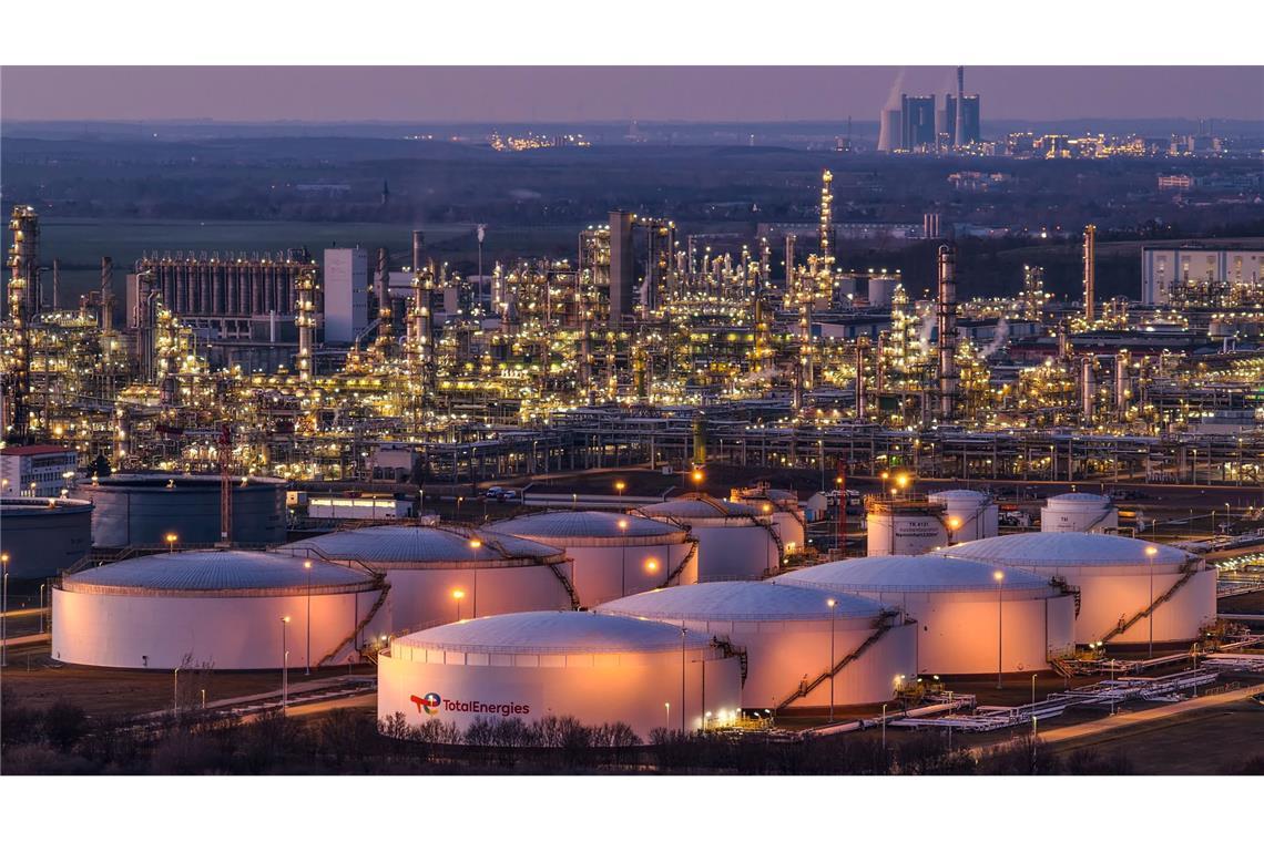 Blick auf die beleuchteten Anlagen der Total Energies Raffinerie im Chemiepark Leuna mit dem Kraftwerk Schkopau im Hintergrund.