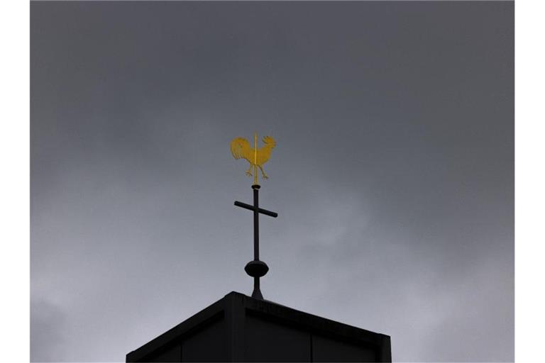 Blick auf ein Kreuz und einen Wetterhahn auf einer Kirche. Foto: Rolf Vennenbernd/dpa
