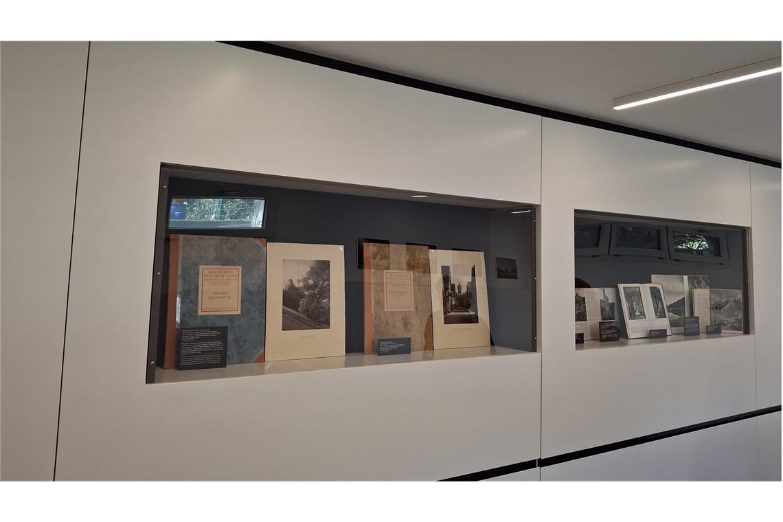 Blick in den  Ausstellungsraum. In den Vitrinen sind Zeugnisse von Otto Lossens Fotoarbeiten, darunter Landschaften und Stadtporträts aus Württemberg, die auch von touristischen Stellen verwendet wurden. Nicht immer wurde der Name Otto Lossen genannt. Bilder aus Fotoserien wie „Bilder aus Schwaben auf Hauff-Platten“ sind auch Teil der Schau.