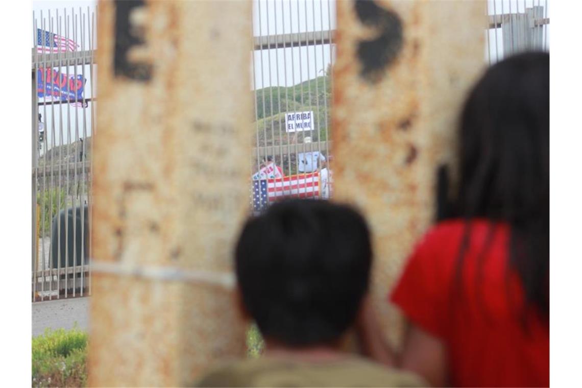 Blick nach drüben: Mexikanische Kinder beobachten durch den Grenzzaun Trump-Anhänger, die eine Verstärkung der Mauer fordern. Foto: Luis Angel Garcia