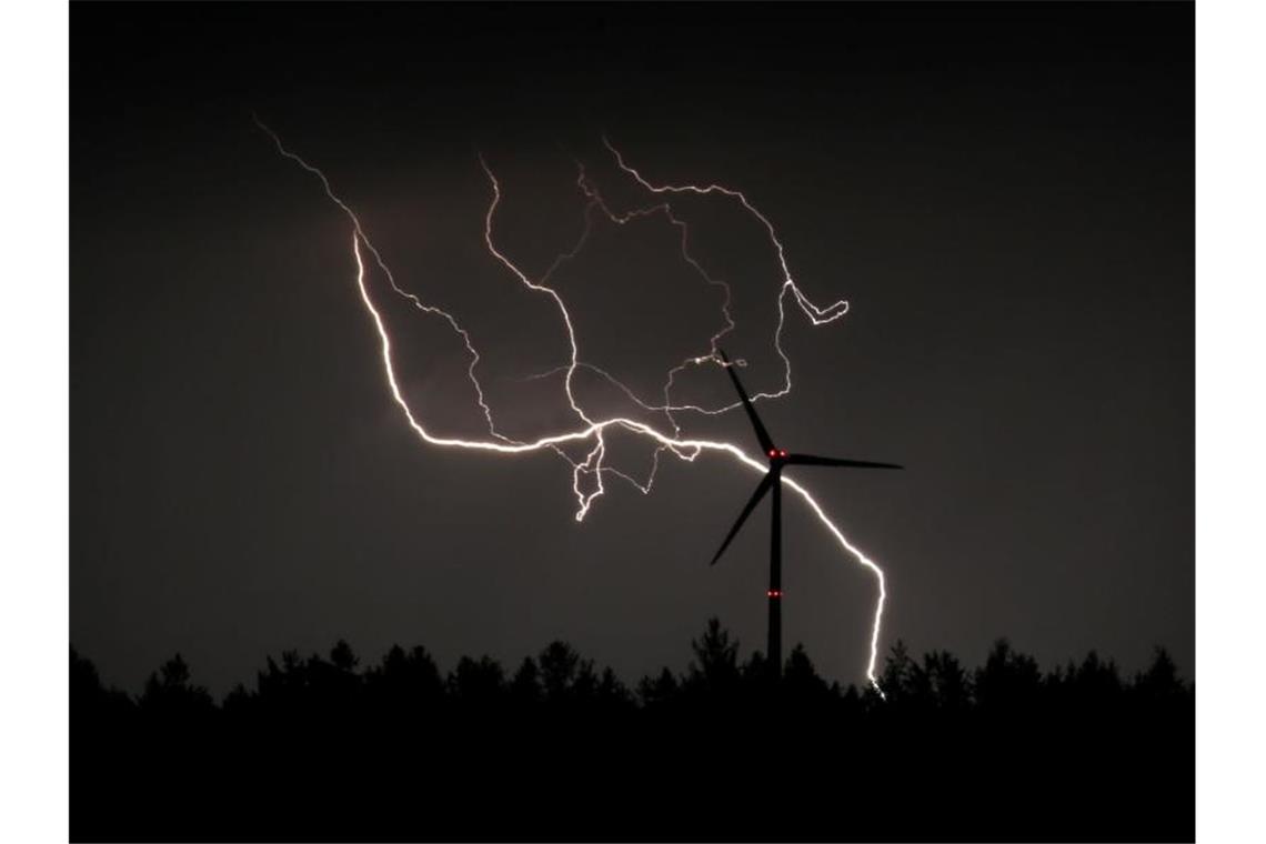 Blitze entladen sich hinter einem Windrad. Foto: Karl-Josef Hildenbrand/dpa/Archivbild