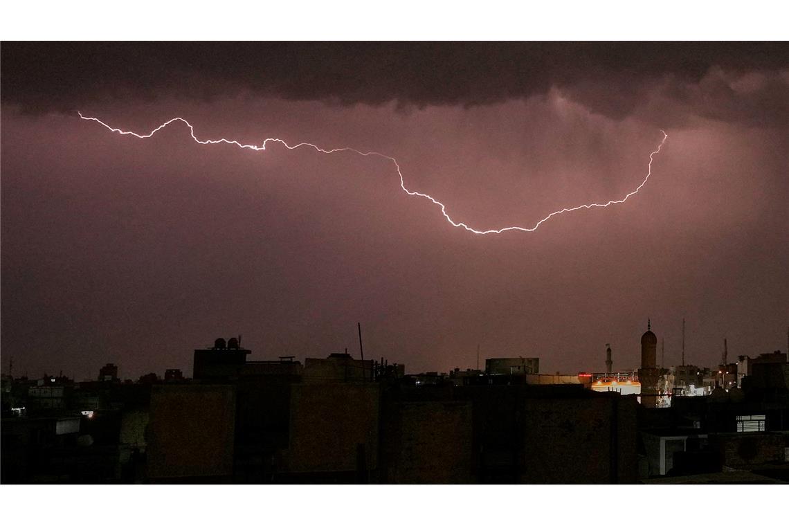 Blitze erhellen den Himmel, während ein Gewitter über Bagdad hinwegzieht.