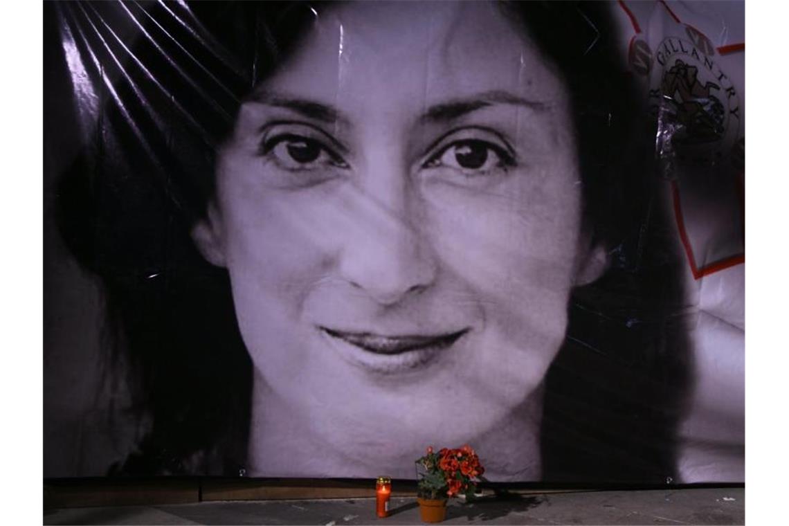 Blumen und eine Kerze liegen vor einem Porträt der ermordeten Enthüllungsjournalistin Daphne Caruana Galizia in Valletta. Foto: Jonathan Borg/AP/dpa