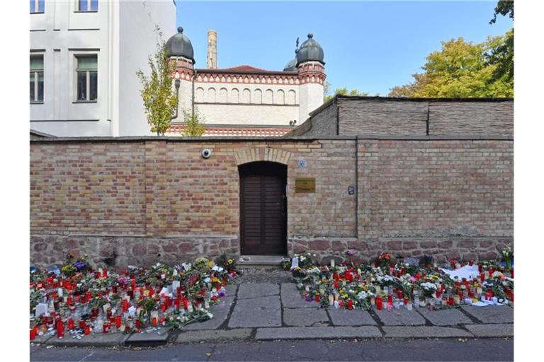 Blumen und Kerzen erinnern an der Synagogentür an den Terroranschlag. Foto: Hendrik Schmidt/dpa-Zentralbild/dpa