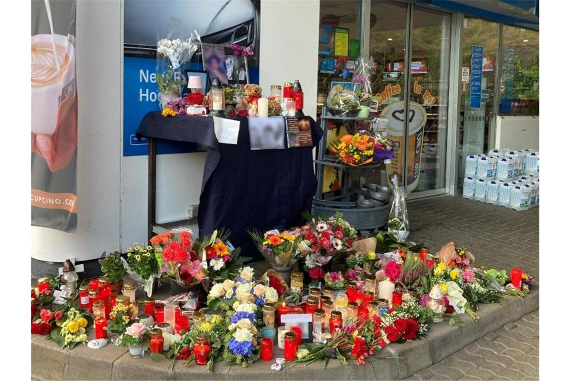 Holpriger Start im Prozess um tödlichen Maskenpflicht-Streit Blumen und Kerzen erinnern an einer Tankstelle in Idar-Oberstein an den jungen Kassierer, der am 18. September 2021 von einem mit einer Pistole bewaffneten Mann erschossen wurde. Foto: Birgit Reichert/dpa